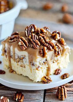 a piece of pecan cheesecake on a white plate with pecans around it