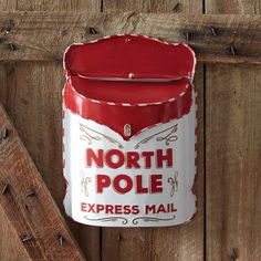 an old north pole express mail box hanging on a wooden fence with nails and nailing