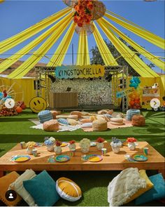 an outdoor party with lots of food on the table and yellow drapes over it