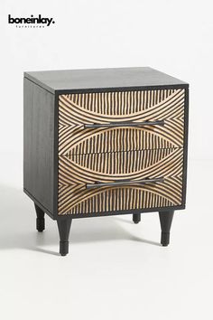 a wooden cabinet with black legs and an abstract design on the front, side view