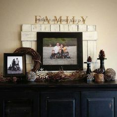 a black dresser topped with pictures and pine cones