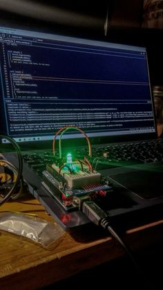 a laptop computer sitting on top of a wooden desk next to a mouse and wires