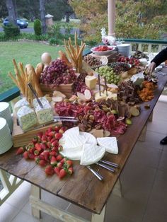 a wooden table topped with lots of different types of cheeses and fruit on top of it