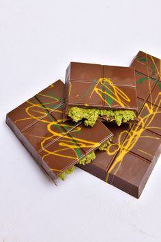 three pieces of chocolate with green and yellow designs on them sitting on top of each other