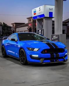 a blue mustang parked in front of a gas station