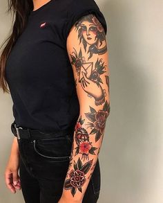 a woman with a tattoo on her arm and shoulder is standing in front of a wall