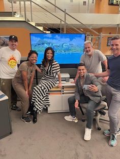 a group of people posing in front of a tv