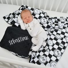 a baby laying on top of a black and white blanket