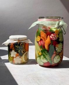 two jars filled with food sitting on top of a white table next to each other