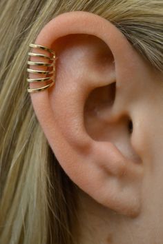 a woman's ear is shown with three gold rings on it