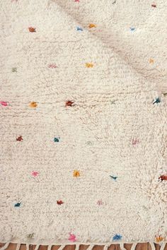 a white rug with multicolored flowers on it sitting on top of a wooden floor