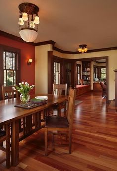 a large dining room with wood floors and red walls, along with an open fireplace