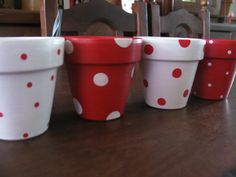 four red and white polka dot flower pots on a table