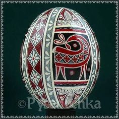 an ornately decorated egg on a black surface with white and red designs in the center