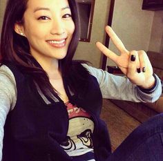 a woman sitting on top of a couch making the v sign with her fingers and smiling at the camera