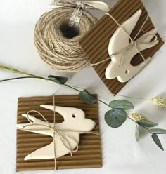 two wooden birds are tied to twine and sitting next to each other on a table