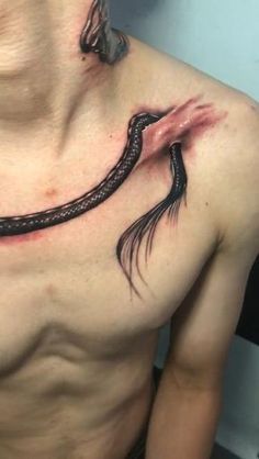 a man with a tattoo on his chest has a snake wrapped around it's neck