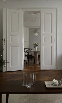 an open door leading into a living room with chairs and table in the background on a wooden floor