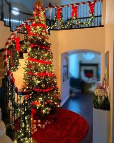 a christmas tree with red and green lights on it in the middle of a staircase