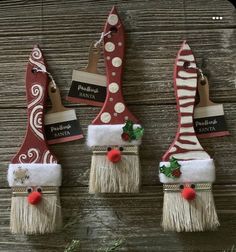 three red and white christmas gnomes with santa hats on them, hanging from a wooden wall