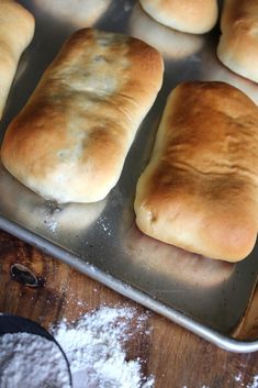 several rolls are sitting on a baking pan with powdered sugar next to the dough