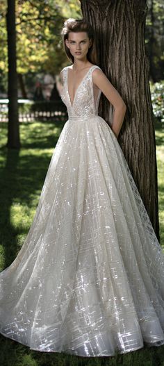 a woman standing next to a tree in a dress