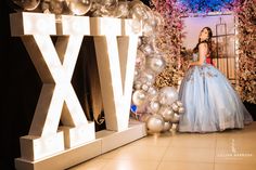 a woman in a blue dress standing next to balloons and letters that spell out the word xx