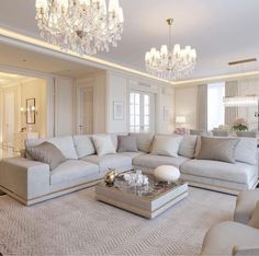 a living room filled with furniture and a chandelier hanging above the couches