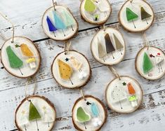 several ornaments are hanging on wood slices with different colors and shapes in the shape of trees