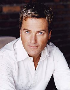 a close up of a person wearing a white shirt and posing for a photo with his hands on his hips