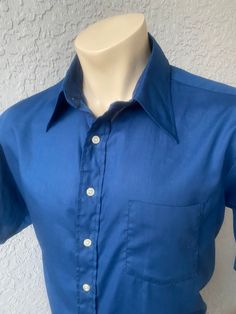 "This deep blue, genuine 1970s vintage, short sleeve, butterfly collared shirt is in excellent vintage condition. SIZE: Pit to Pit: 25\" Collar to hem: 31\" Sleeves: 11\" The tag does not have a size. Check the measurements. I would say it fits like a roomy XL The male mannequin would be 5'10\" 170 lbs. ITEM 125" Classic Blue Shirt For Summer, Blue Short Sleeve Shirt With Spread Collar For Summer, Formal Cotton Shirt With Short Sleeves, Classic Cotton Formal Short Sleeve Shirt, Solid Vintage Summer Shirt, Formal Short Sleeve Cotton Shirt, Blue Spread Collar Short Sleeve Shirt For Spring, Blue Short Sleeve Shirt With Spread Collar For Spring, Vintage Fitted Shirt For Summer