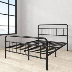 a black metal bed frame sitting on top of a hard wood floor next to a window