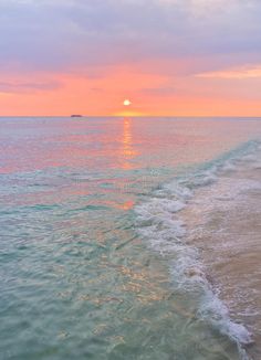 the sun is setting over the water at the beach