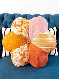 a blue couch with pillows on top of it and an umbrella shaped pillow in the middle