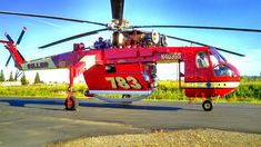 a red helicopter sitting on top of an airport tarmac