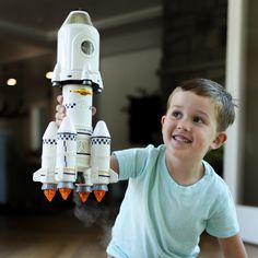 a young boy holding up a toy rocket ship