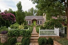 a white picket fence in front of a house with green door and steps leading up to it