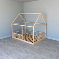 a wooden doll house bed in a room with light blue walls and wood flooring