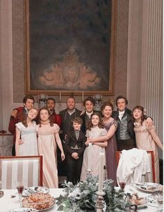 a group of people standing in front of a table with plates and silverware on it