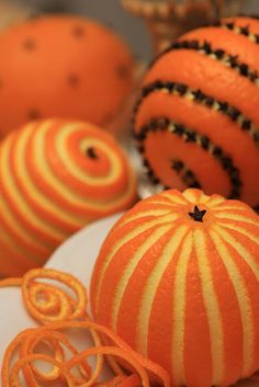 some oranges are sitting on a plate and one is decorated with black beads, the other has an ornament