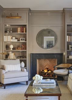 a living room filled with furniture and a fire place in front of a book shelf