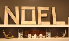 a shelf with candles and other items on it in front of a sign that says noel