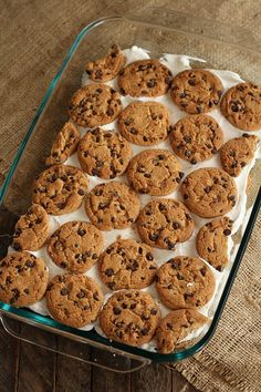 a glass baking dish filled with cookies on top of a wooden table