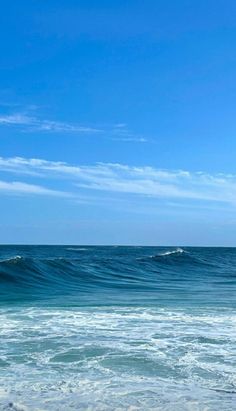 a person riding a surfboard on top of a wave in the ocean with blue skies