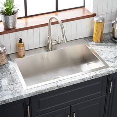 a kitchen sink sitting under a window next to a counter