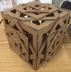 a cube made out of cardboard sitting on top of a wooden table