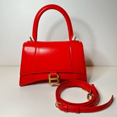 Condition : New With Box And Dustbag Size: Length: 9 In Height: 5.5 In Width: 4 In Drop: 3.5 In Drop: 13 In Description: This Is An Authentic Balenciaga Shiny Box Calfskin Small Hourglass Top Handle Bag In Bright Red. This Stylish And Structured Handbag Is Crafted Of Smooth Calfskin Leather. The Bag Features A Sturdy Leather Top Handle With Aged Goldlinks, A Prominent B Logo On The Front Flap, And An Optional, Adjustable Shoulder Strap. The Front Flap Opens With A Magnetic Snap Closure To A Smoo Evening Double Handle Box Bag With Original Box, Luxury Red Rectangular Shoulder Bag, High-end Red Shoulder Bag With Branded Hardware, Designer Red Rectangular Shoulder Bag, Luxury Red Box Bag For Shopping, Designer Red Office Bag, Classic Red Box Bag With Top Carry Handle, Luxury Red Top Handle Bag, High-end Red Crossbody Shoulder Bag