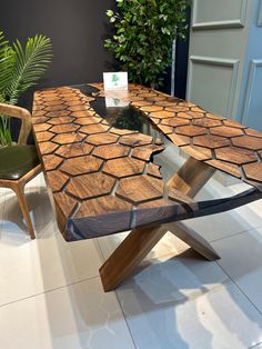 a wooden table sitting on top of a white tile floor next to a green plant