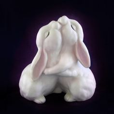 a white rabbit statue sitting on top of a black floor next to a purple background