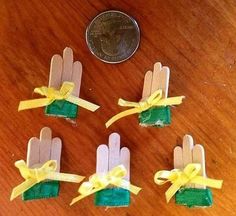 four small plastic gloves with yellow ribbons tied around them on a table next to a penny